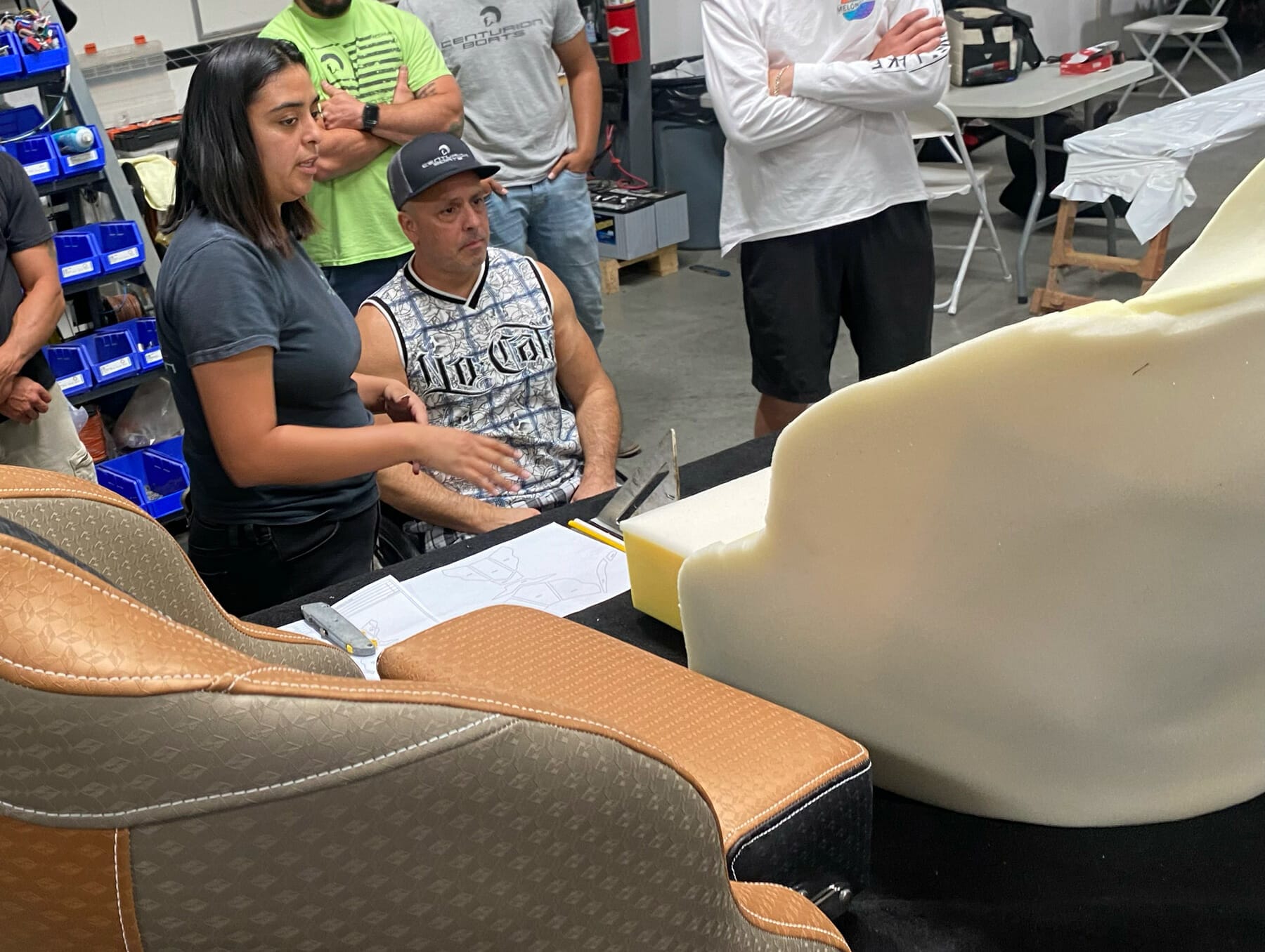 A group of people inspecting a Custom Boat Seat at a workshop.
