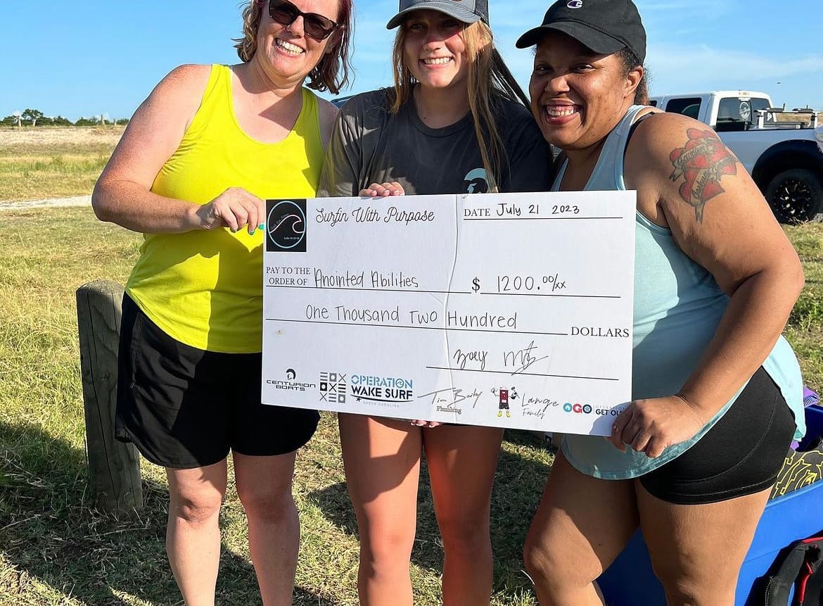 Three women posing for a picture with a check.