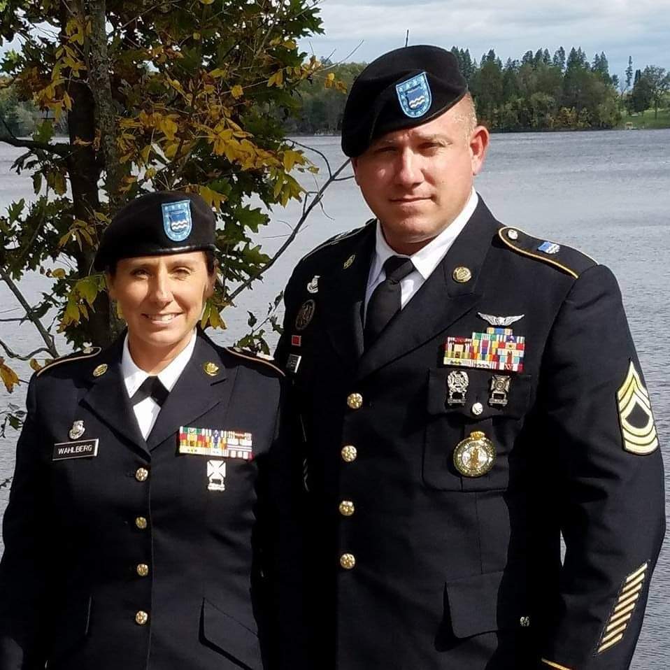 A man and woman in uniform standing next to a body of water.