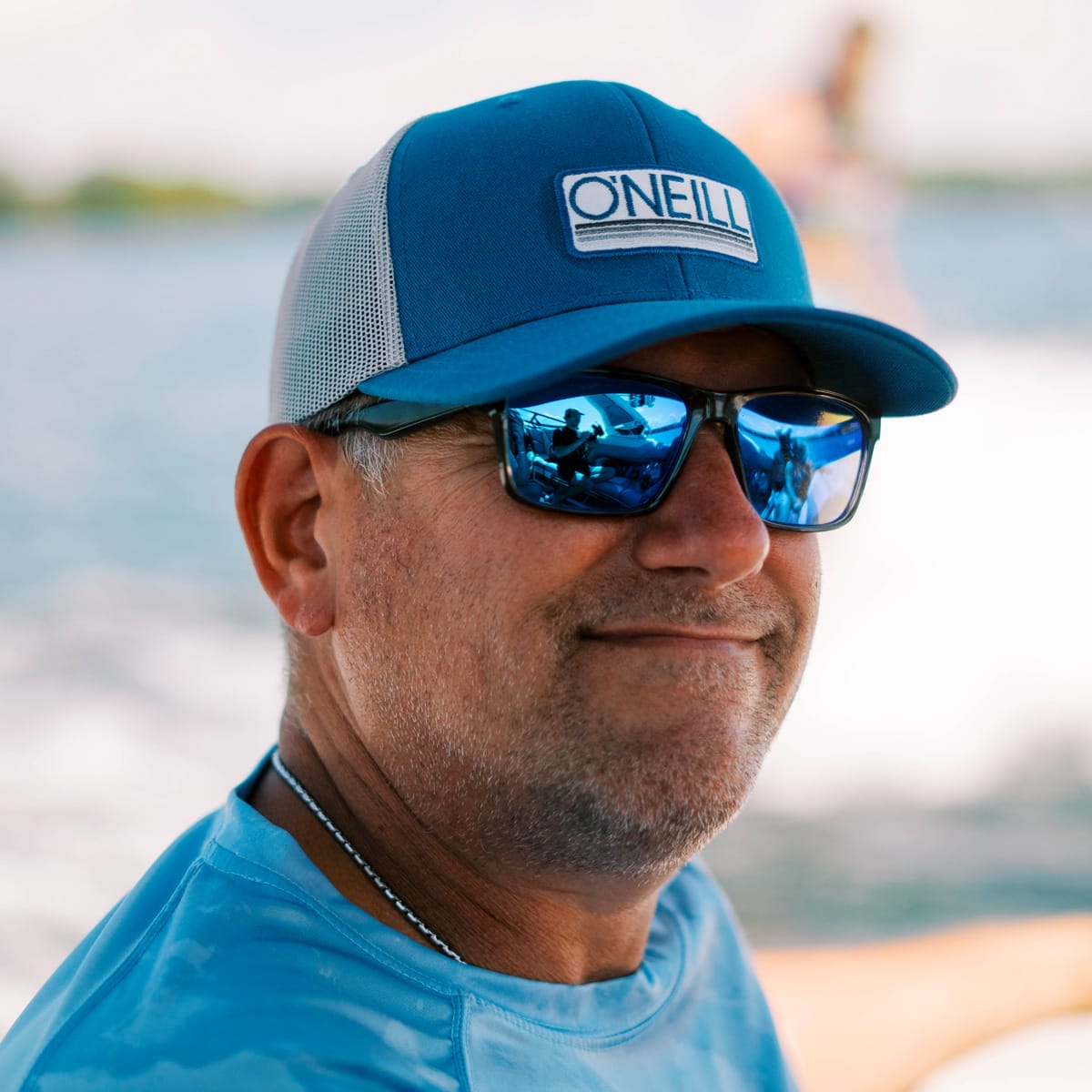 A man wearing sunglasses and a hat on a boat.