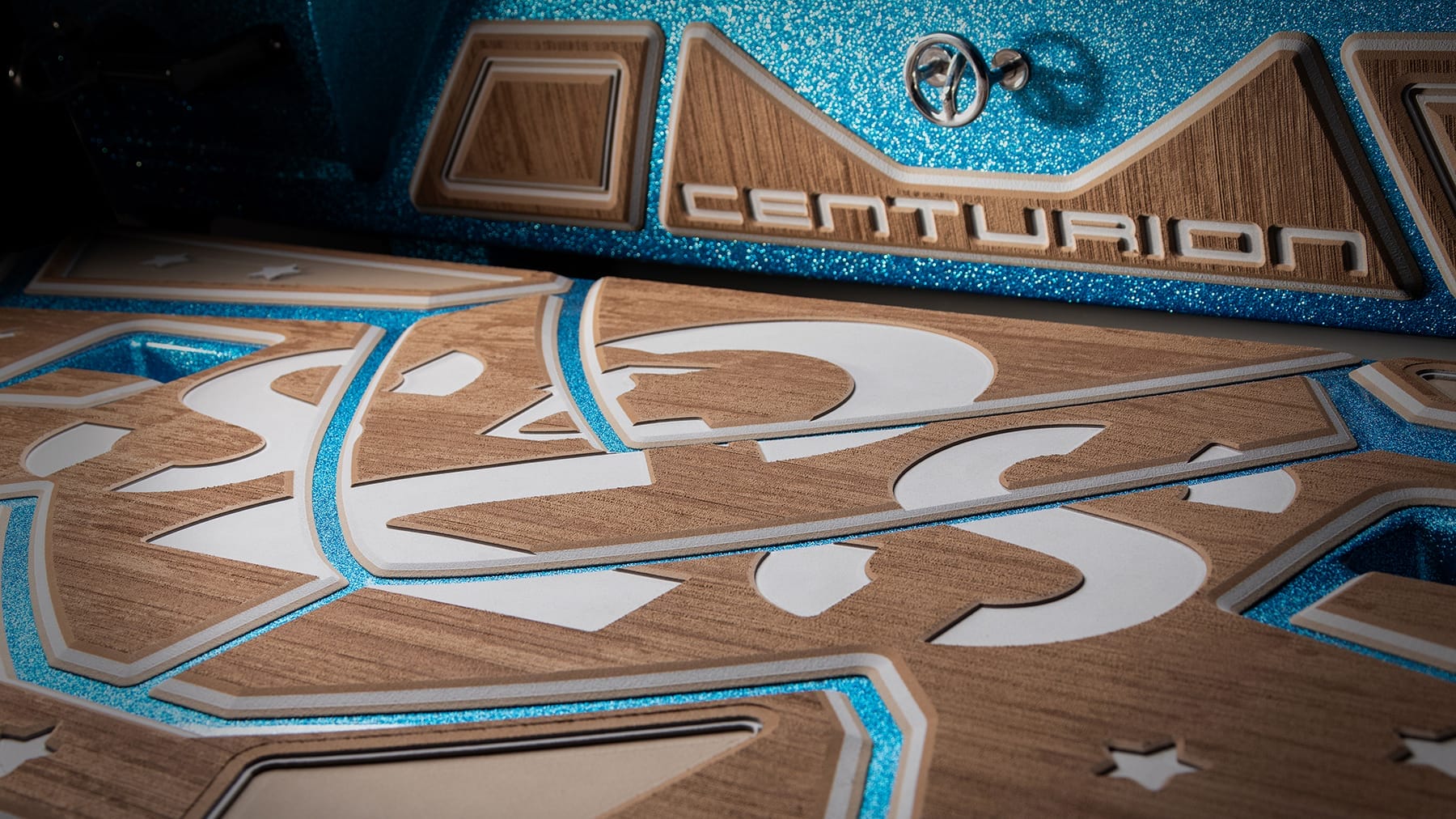 Close-up of a Centurion logo on a boat with a detailed wooden design and blue metal accents.