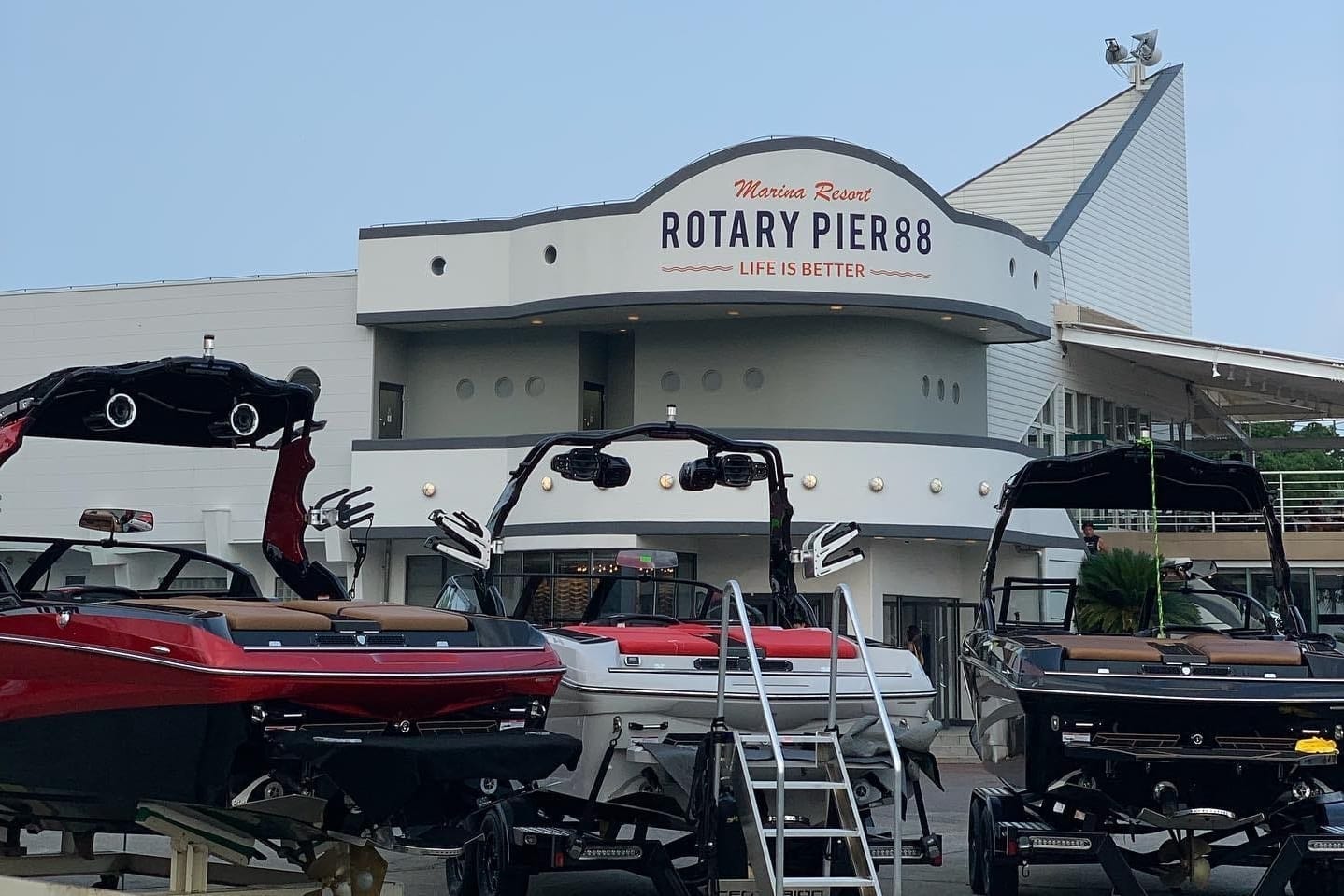 Front view of Rotary Pier 88 at Mansa Resort, showcasing several docked boats and the entrance to the pier building with signage 